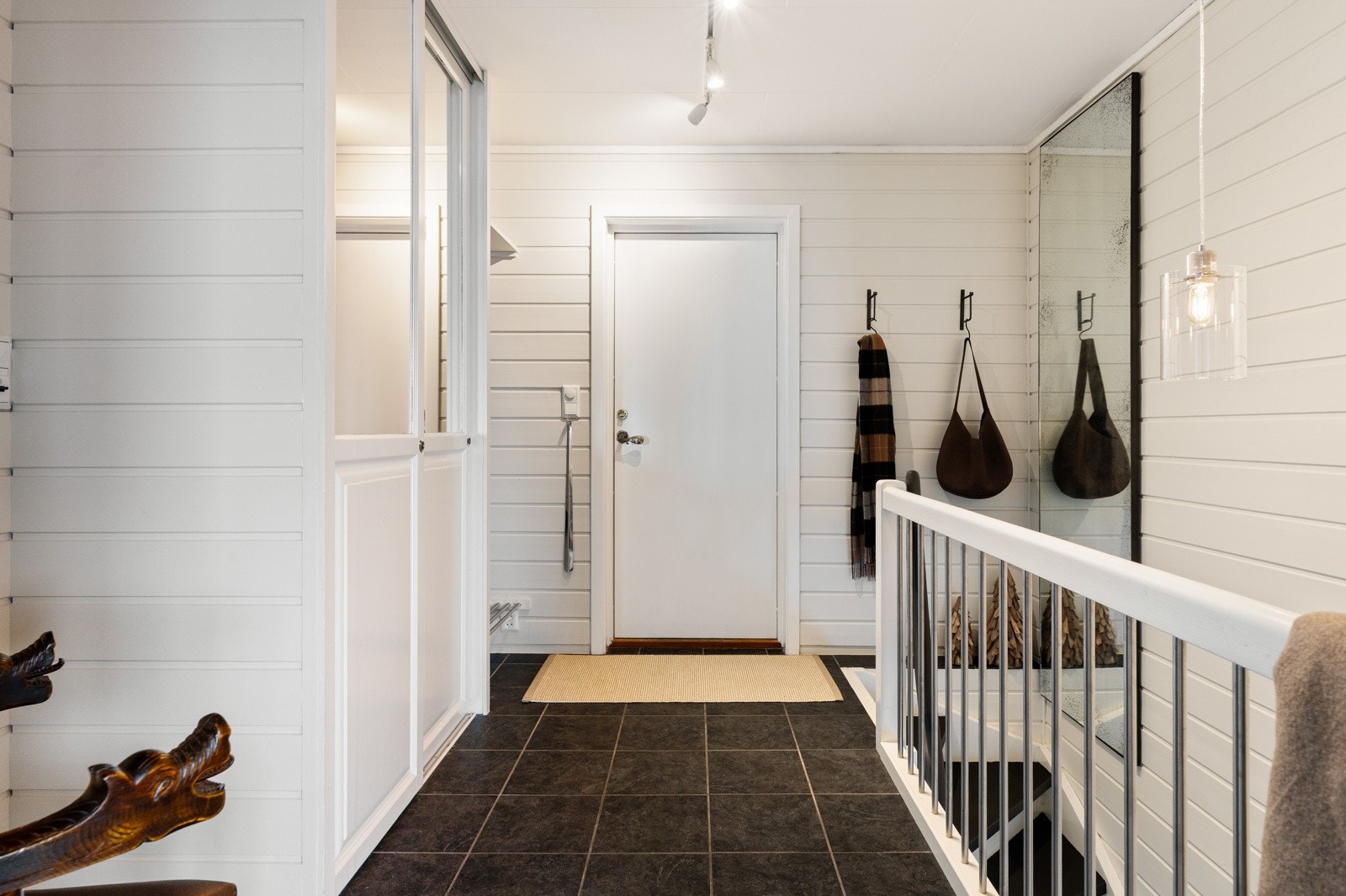 Boligen tar deg i mot i en lys og romslig gang. Med flislagt gulvparti og liggende panel på vegg. Galleribilde