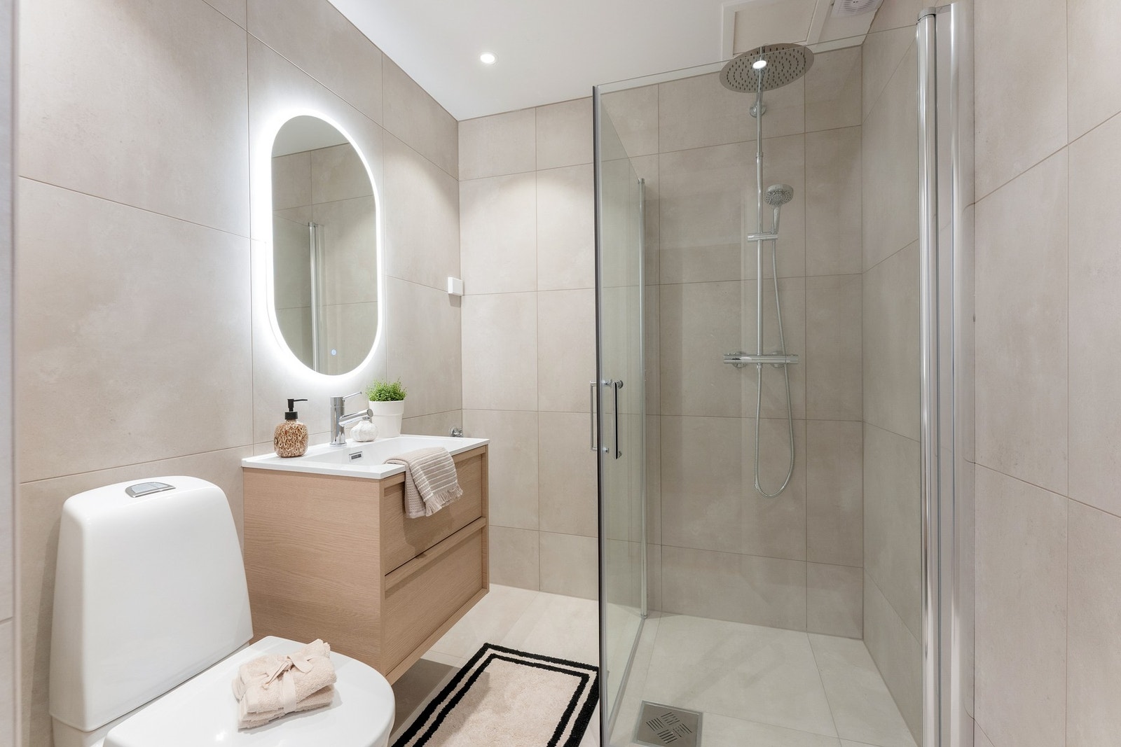 Videre er det servantskap med glatte, folierte fronter og heldekkende servant. Speil på vegg over servant. Galleribilde