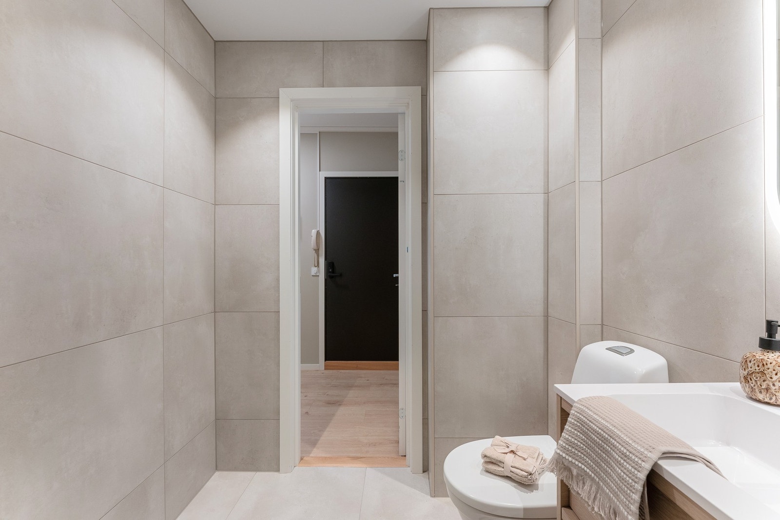 Dusjhjørne med svingdører, sluk i sone, regnfallsdusj og termostatstyrt blandebatteri, og gulvmontert toalett. Galleribilde