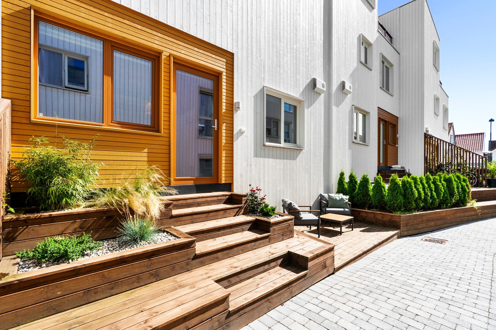 Her er det opparbeidet med tredekke og plassbygde blomsterkasser, trappeløsningen er romslig og det nederste trinnet fungerer også som ekstra sitteplass. Galleribilde