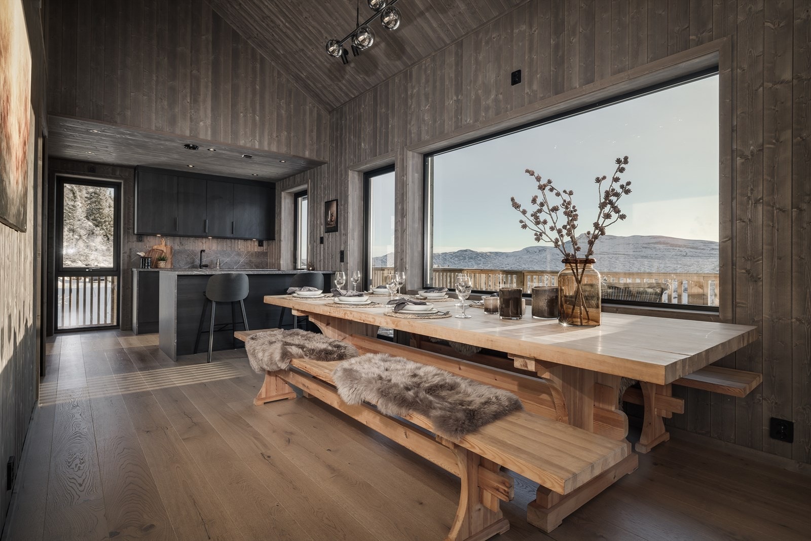 Lekkert kjøkken med åpen løsning og direkte utgang til solrik terrasse som strekker seg rundt hytta. Galleribilde