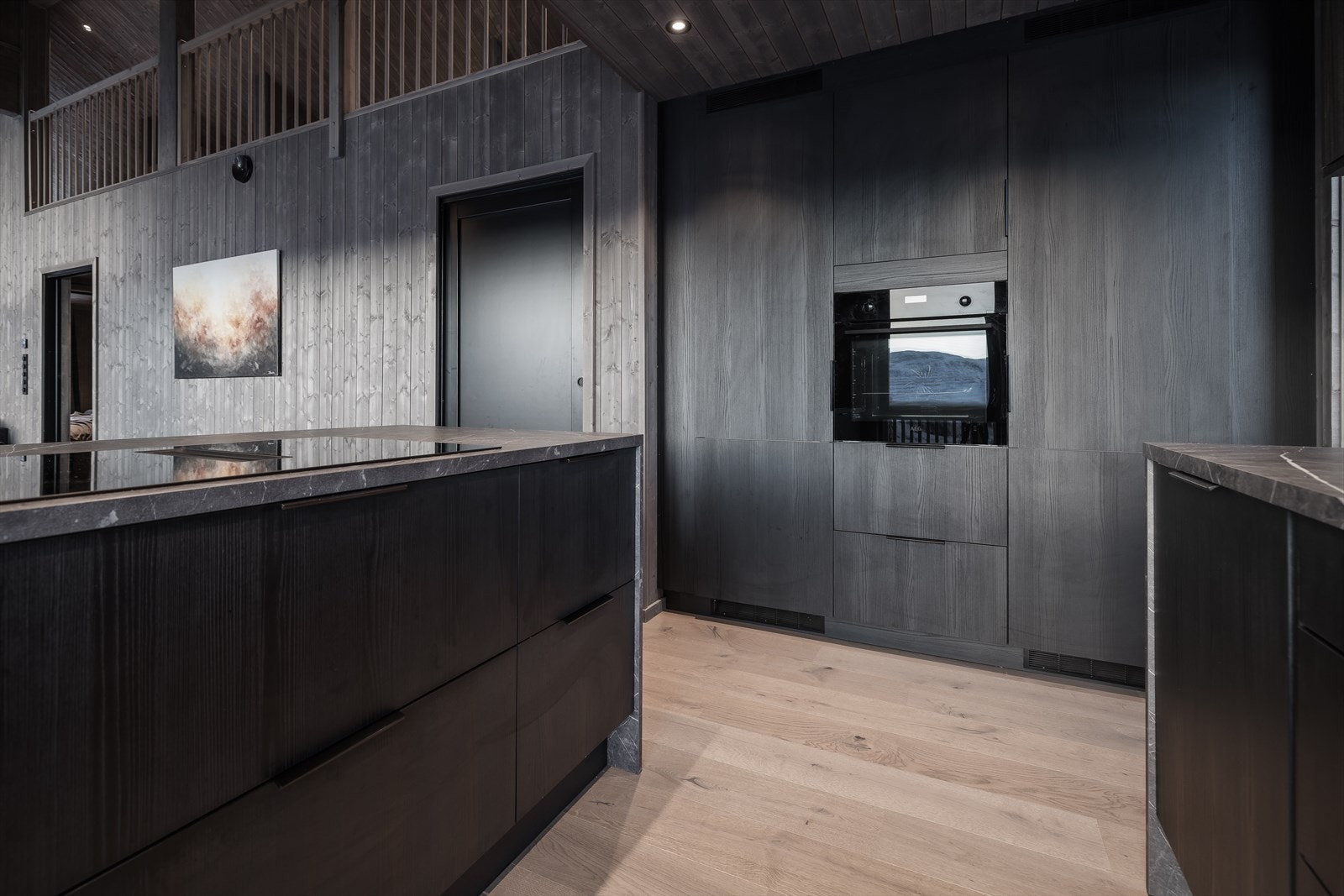 Romslig kjøkken med smarte løsninger som kokeplate med innebygd kjøkkenvifte. Galleribilde