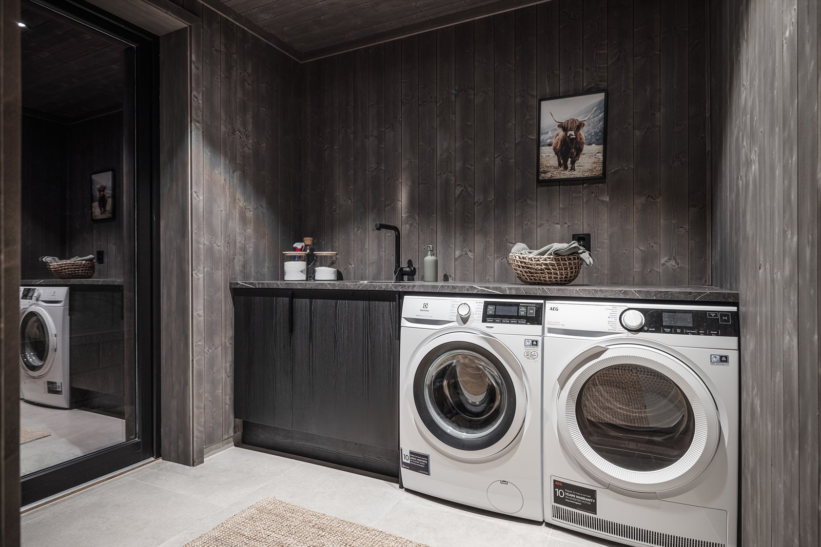 Gjennomført bod med integrert benk, oppbevaring og plass til vaskemaskin og tørketrommel. Galleribilde