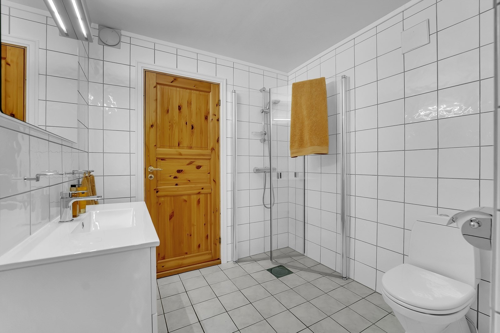 Badet i underetasjen ble oppgradert i 2015 med ny baderomsinnredning, dusjdører, toalett og speil med belysning. Rommet har hvite fliser på vegger og grå fliser på gulv, og fremstår lyst og tidløst. Galleribilde