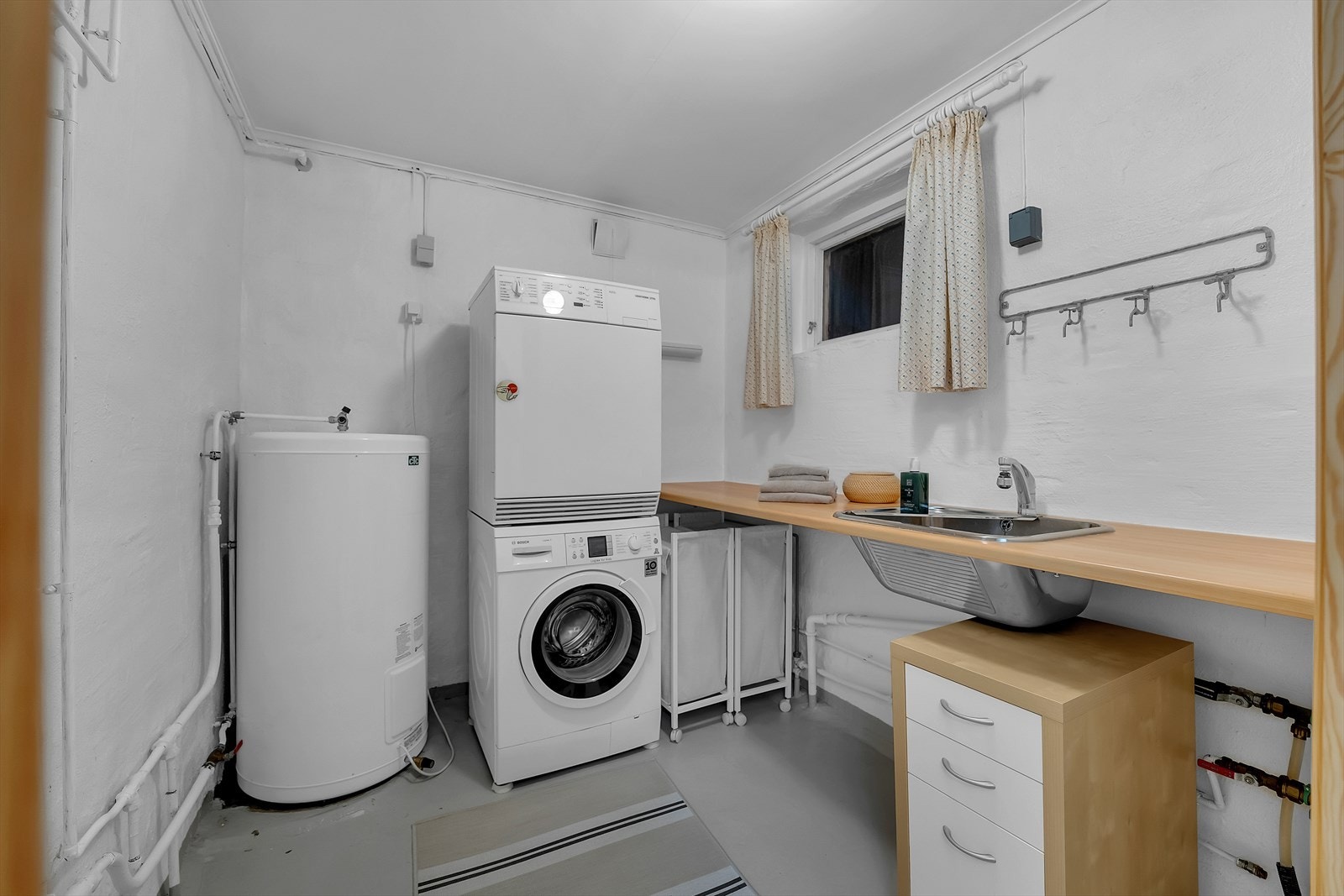 Vaskerommet er utstyrt med opplegg for vaskemaskin, laminat benkeplate med nedfelt utslagskum og varmtvannsbereder på 194 liter fra 2018. Et funksjonelt rom som gjør hverdagen enklere. Galleribilde