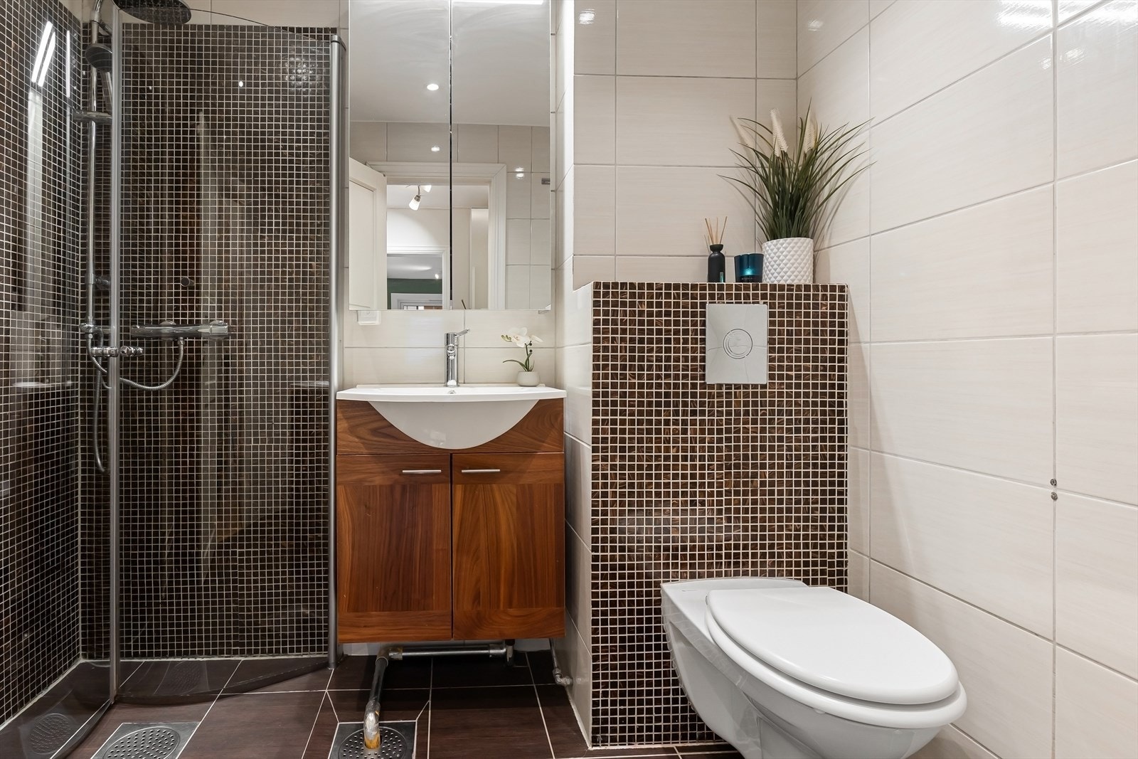 Delikat bad med dusjnisje, vegghengt wc, servant med underskap og speilskap. Galleribilde