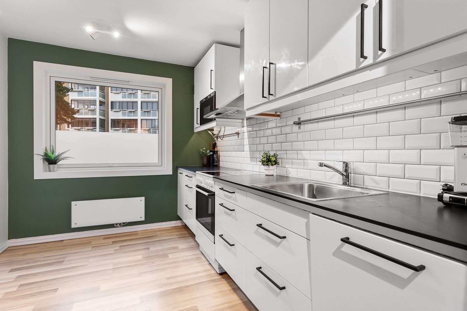 Kjøkken med fliser på vegg mellom benkeplate og skap. Galleribilde