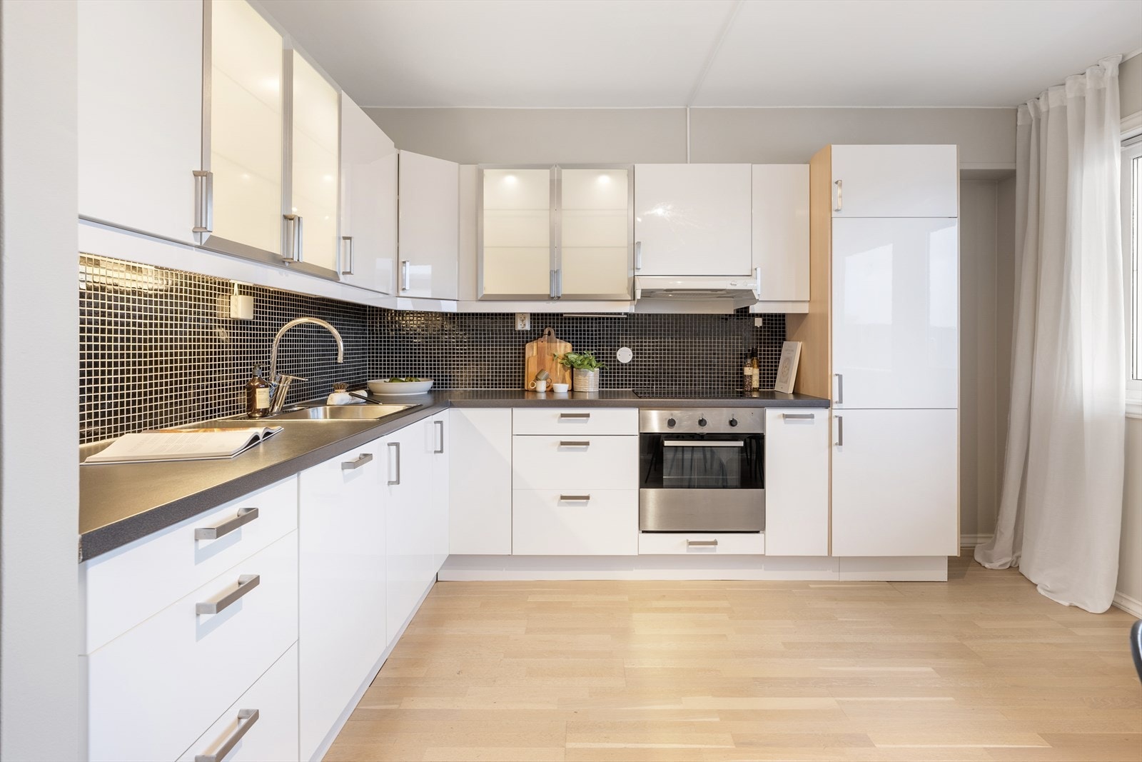 Kjøkkenet har hvite slette fronter og benkeplate i laminat. Galleribilde