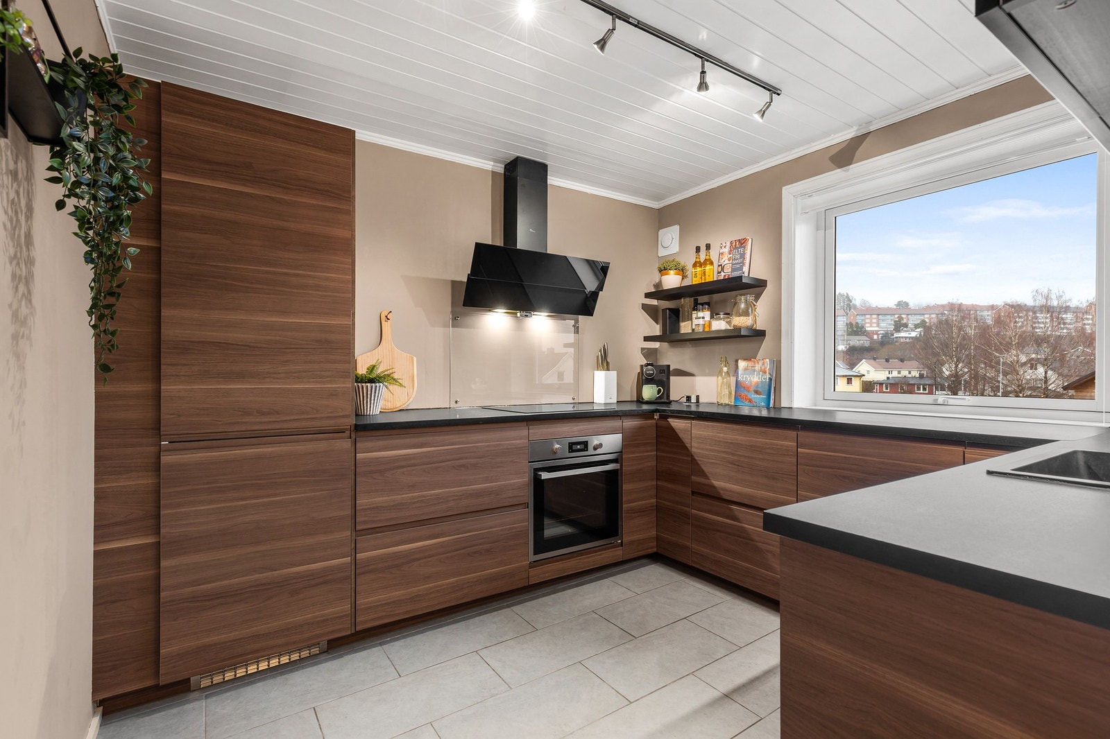 Innredningen har integrerte hvitevarer, herunder kjøl/fryseskap, oppvaskmaskin, platetopp og stekeovn Galleribilde