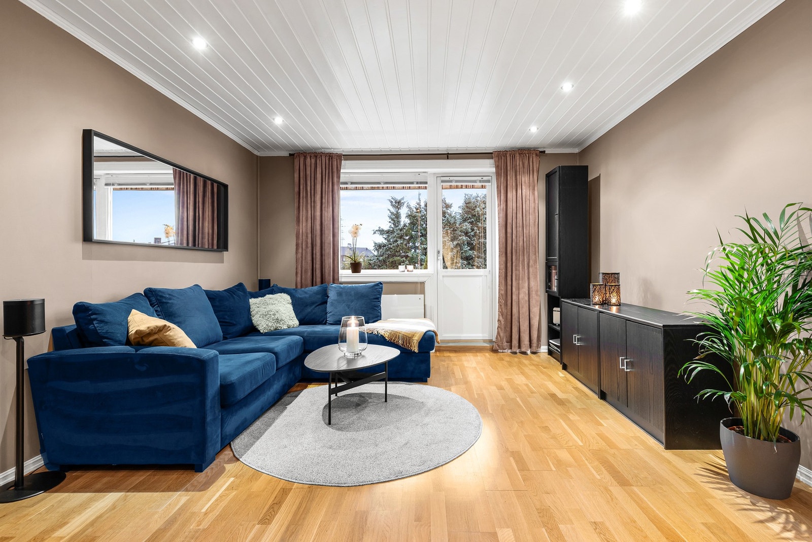 Stue med parkett på gulv, slette flater på vegger og panel samt downlights i himling Galleribilde