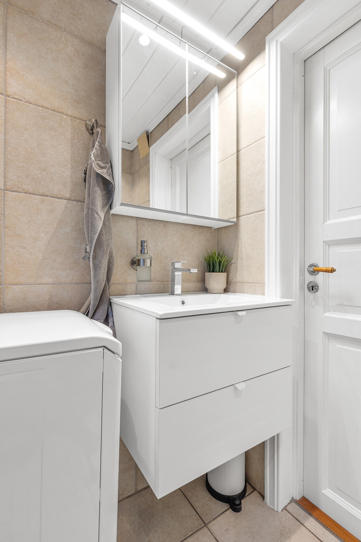 Rommet er innredet med vegghengt toalett, dusjhjørne, servant i innredning og opplegg for vaskemaskin Galleribilde