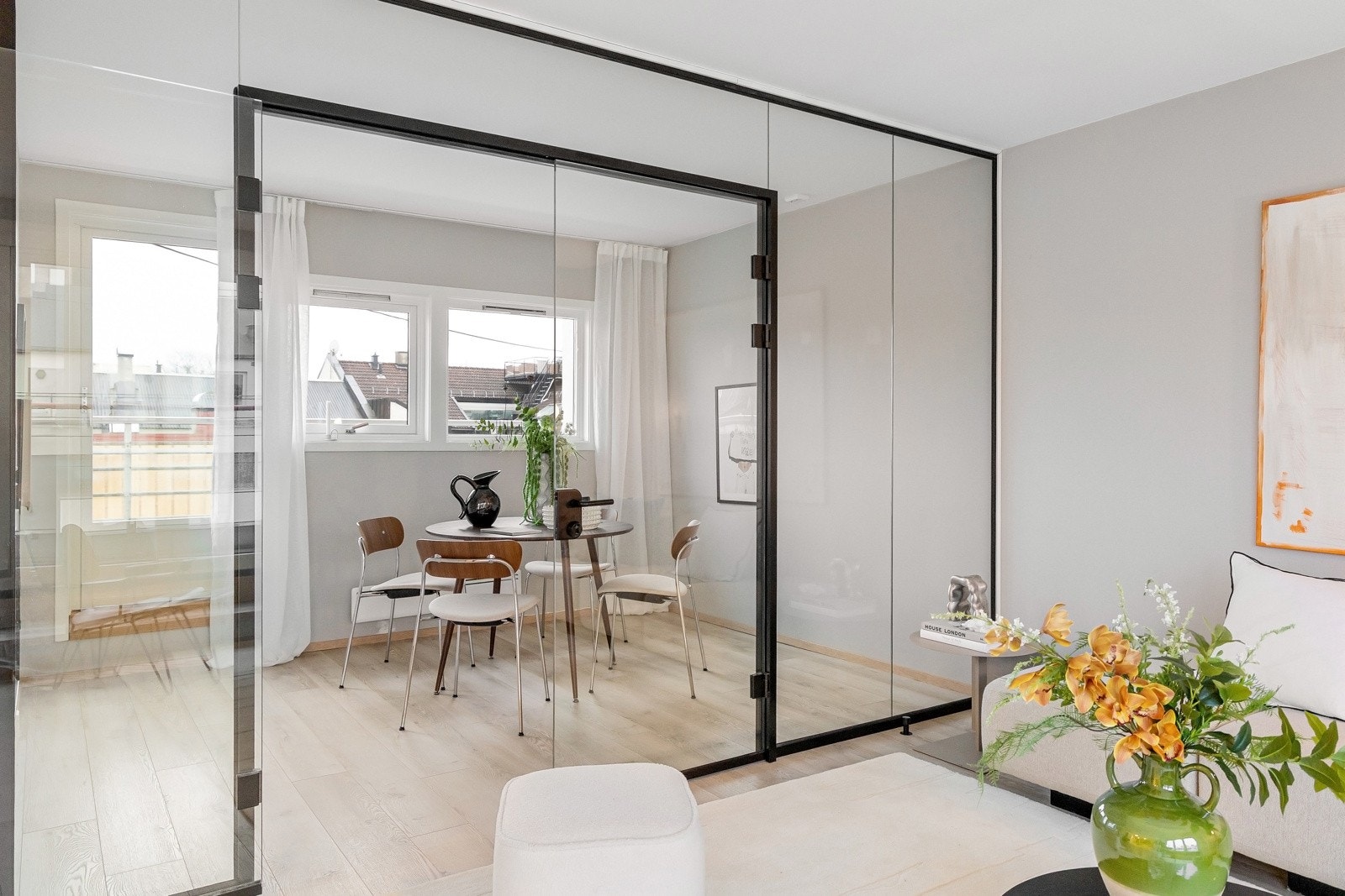 Fra stuen kommer du inn i leilighetens spisestue gjennom en moderne glassvegg med glassdører og sorte detaljer. Galleribilde