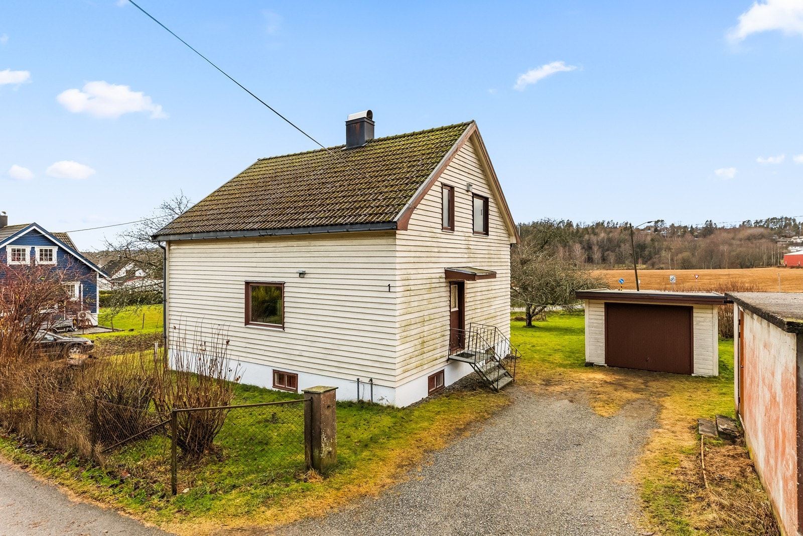 Eiendommen ligger på en relativt flat tomt med gruset innkjørsel og gressarealer. Galleribilde
