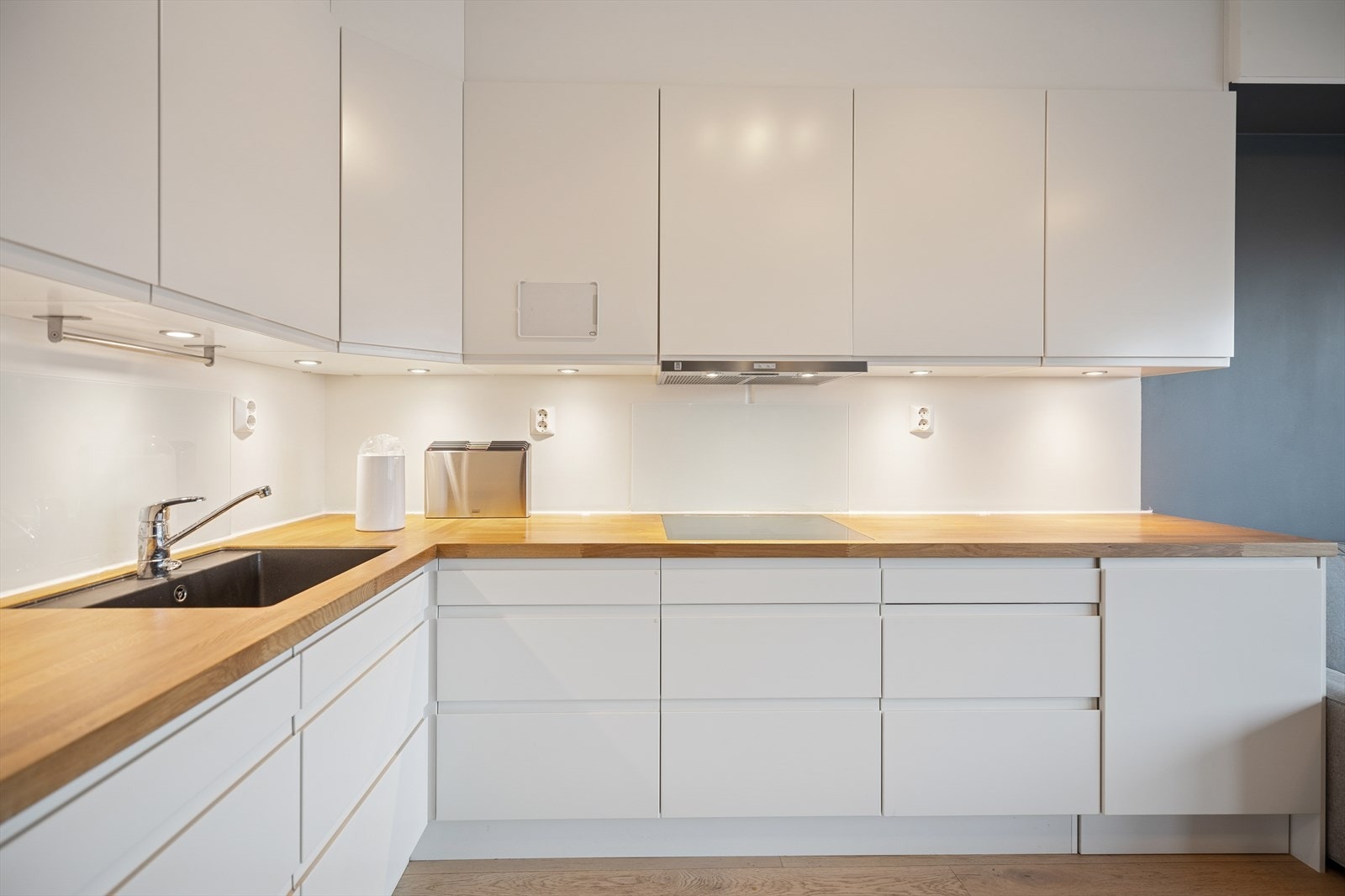 Lekkert kjøkken med glatte fronter og heltre benkeplate med planlimt kum i rustfritt stål. Integrerte hvitevarer som Induksjonstopp, stekeovn og oppvaskmaskin, samt plass til frittstående kjøleskap. Galleribilde