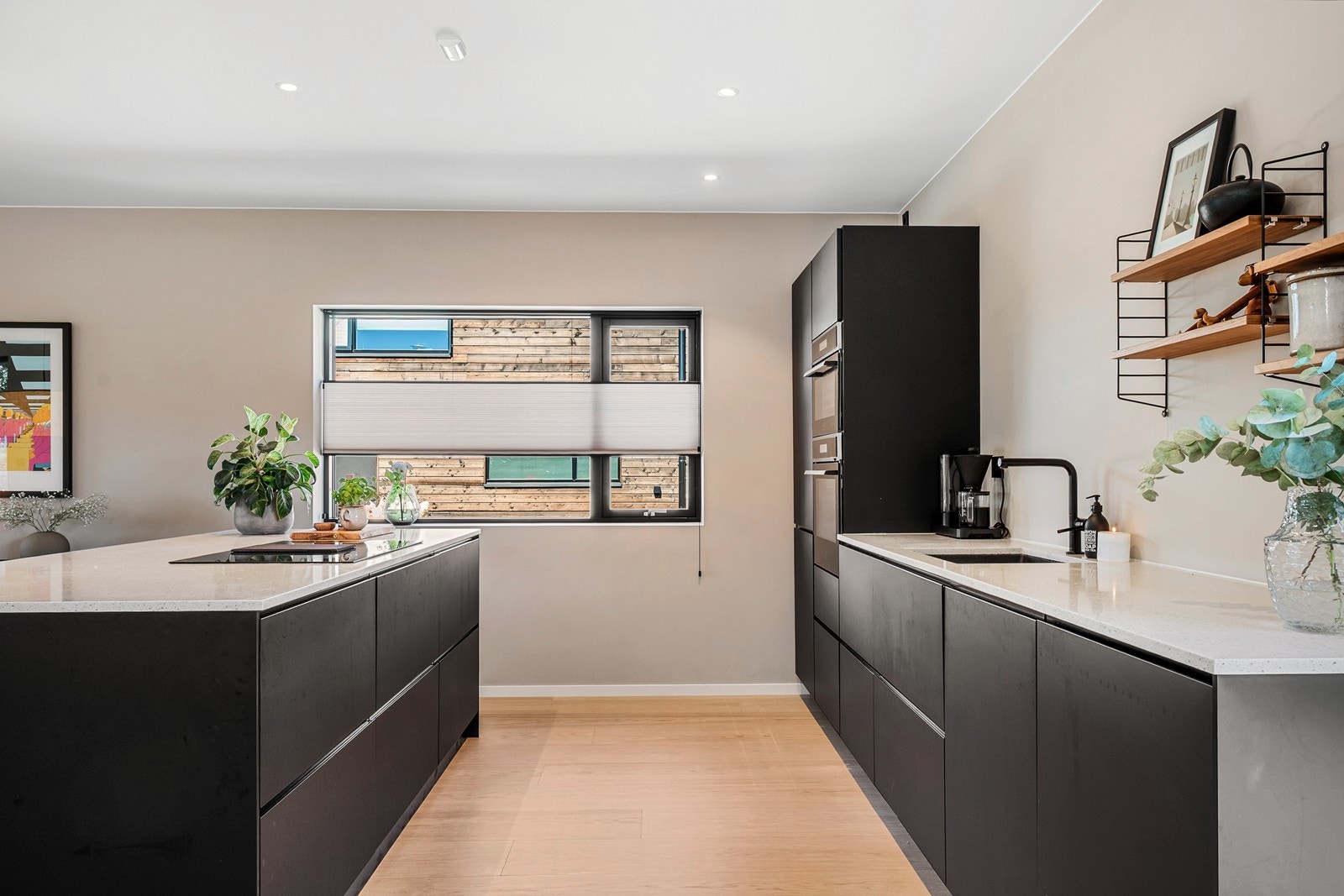 Kjøkkenet har et moderne og funksjonelt design med slette, sorte fronter og lys benkeplate i polert stein. Galleribilde