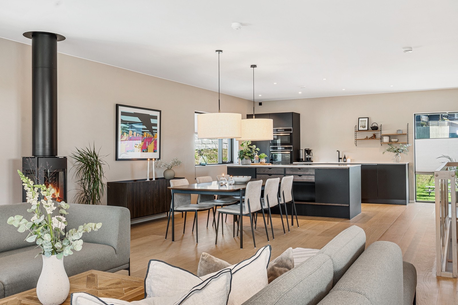 Stue og kjøkken er plassert i en åpen løsning med naturlige soner for både spiseplass og sofagruppe. Galleribilde