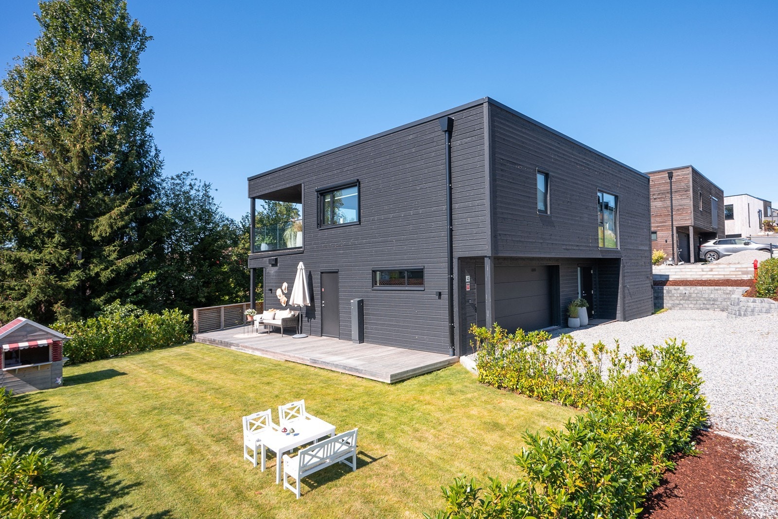 Tomten er pent opparbeidet med hekk og gruset gårdsplass som skaper et velstelt førsteinntrykk. Utvendige screens sørger for effektiv solskjerming og redusert innsyn. Galleribilde