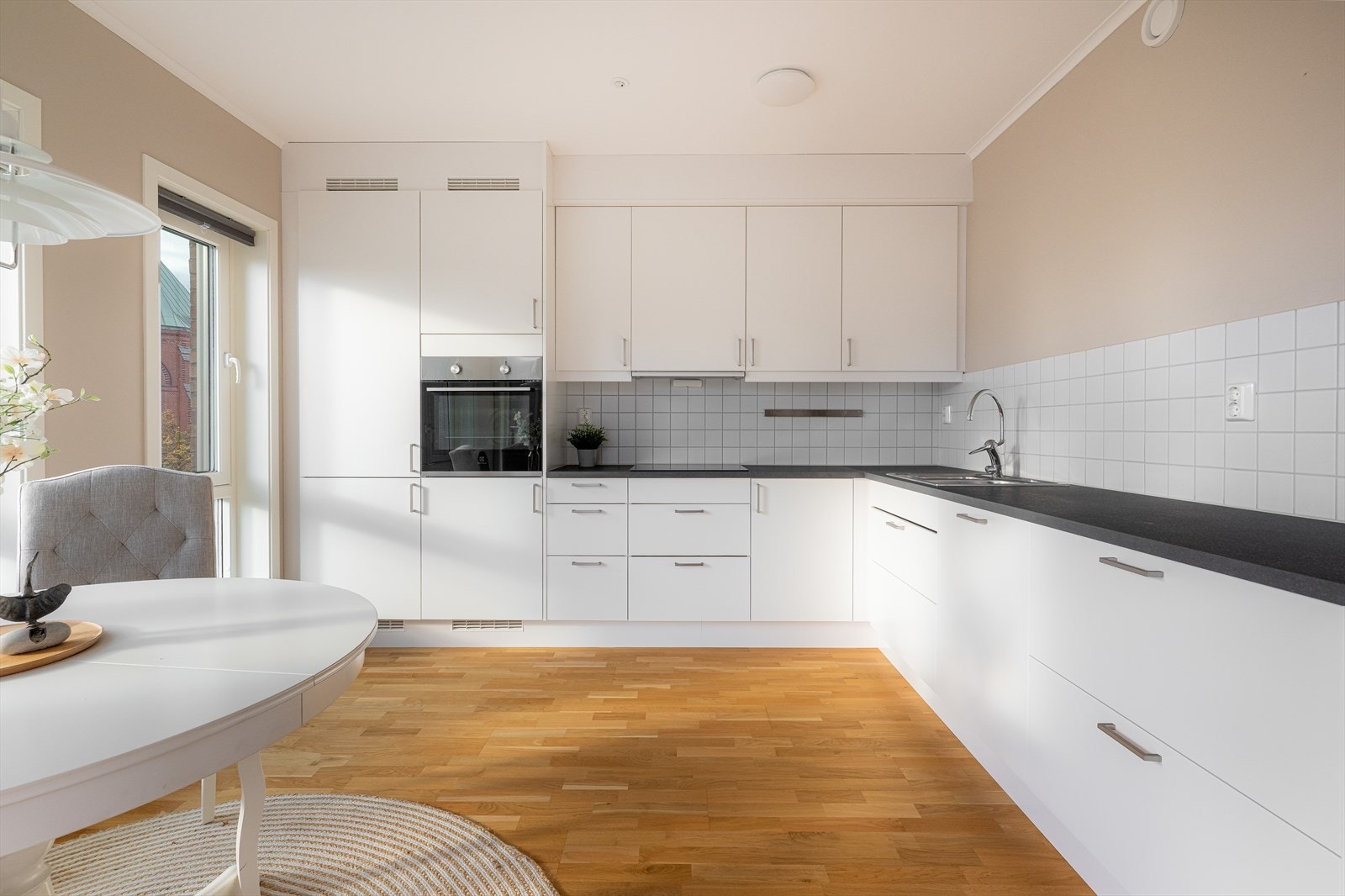 Kjøkkenet har stilren laminatbenkeplate med nedfelt oppvaskkum og induksjonsplatetopp, samt kjøkkenventilator med effektivt avtrekk. Flis mellom over- og underskap gjør rengjøringen enkel og beskytter veggen. Galleribilde