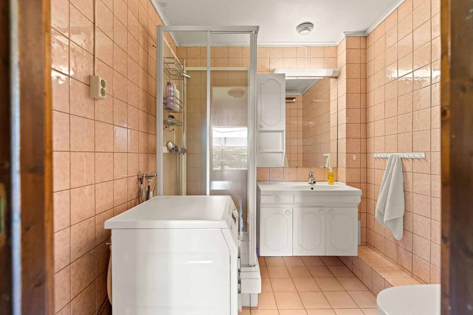 Baderommet har flislagte gulv og vegger. Rommet har dusjkabinett, gulvstående klosett og servant med benkeskap. I tillegg er det opplegg for vaskemaskin. Rommet har fått TG2 og TG3. Galleribilde