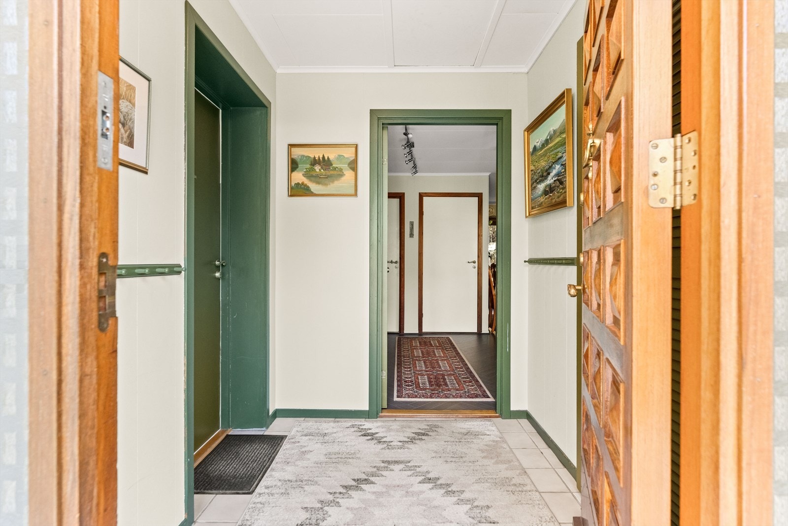 Entréen deles mellom hoveddelen og leiligheten i 1. etasje. Yttergangen har fliser på gulvet. Videre er det inngang til en innergang/hall, med plass til garderobeløsning. Galleribilde