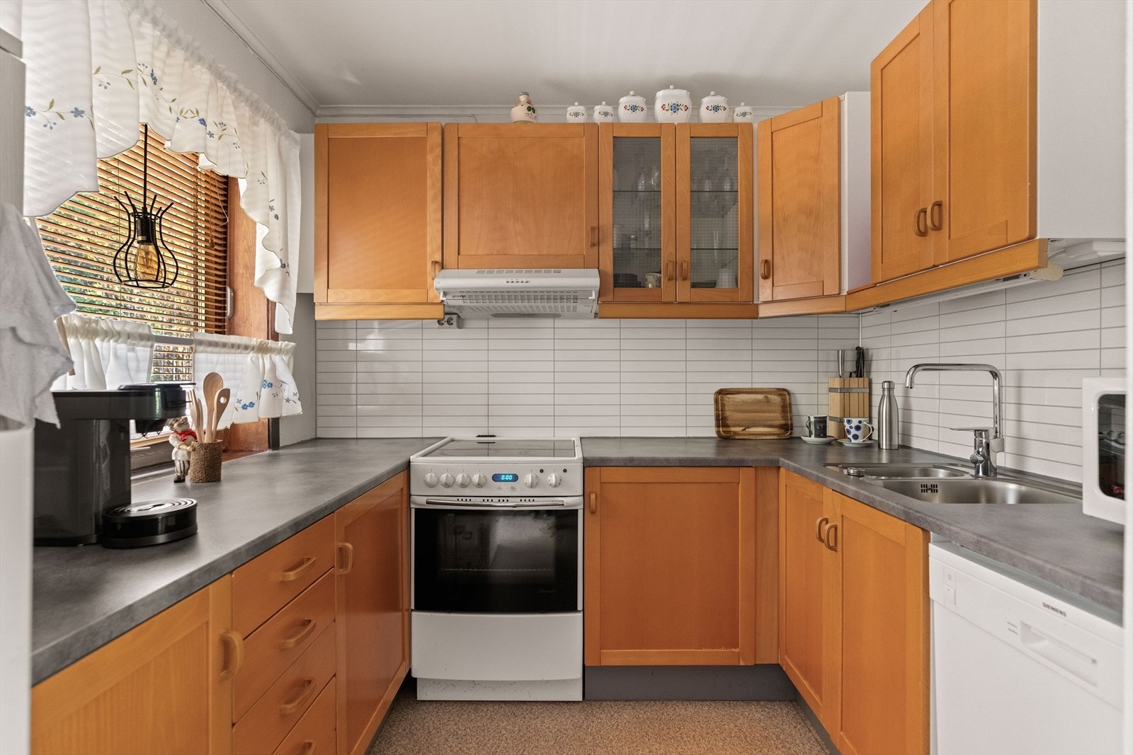 Innredningen har skap med profilerte fronter, samt laminat benkeplate. Det er plass til frittstående hvitevarer samt opplegg for oppvaskmaskin. Galleribilde