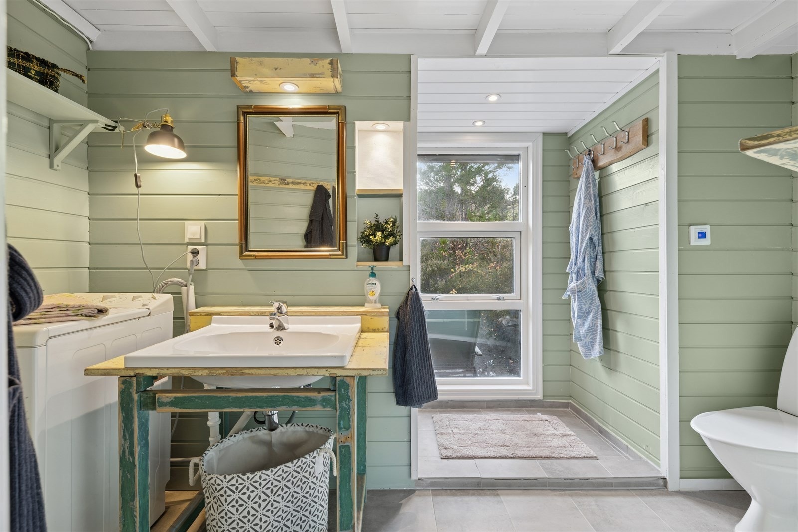 Baderommet er nylig modernisert med egeninnsats og flott innredet med grå fliser på gulv og i dusjsone og ellers malt panel på vegg. I gulvet har man også varmekabler for ekstra komfort. Galleribilde