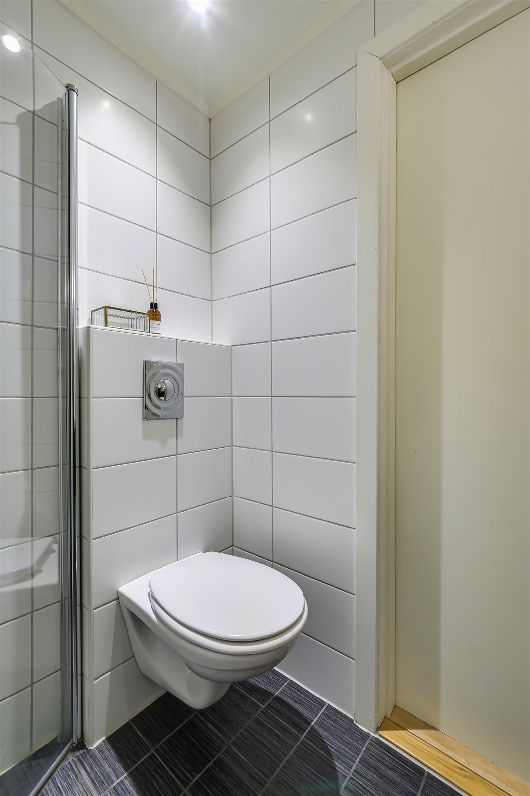 Badet har vegghengt toalett, flislagt gulv med varmekabler, flislagte vegger og malt himling. Galleribilde