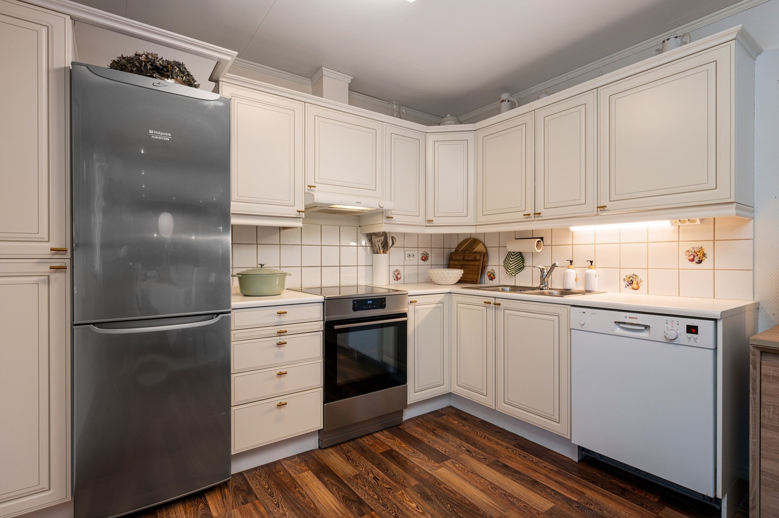 Pent kjøkken bestående av frittstående komfyr, oppvaskmaskin og kjøleskap med fryser. Galleribilde