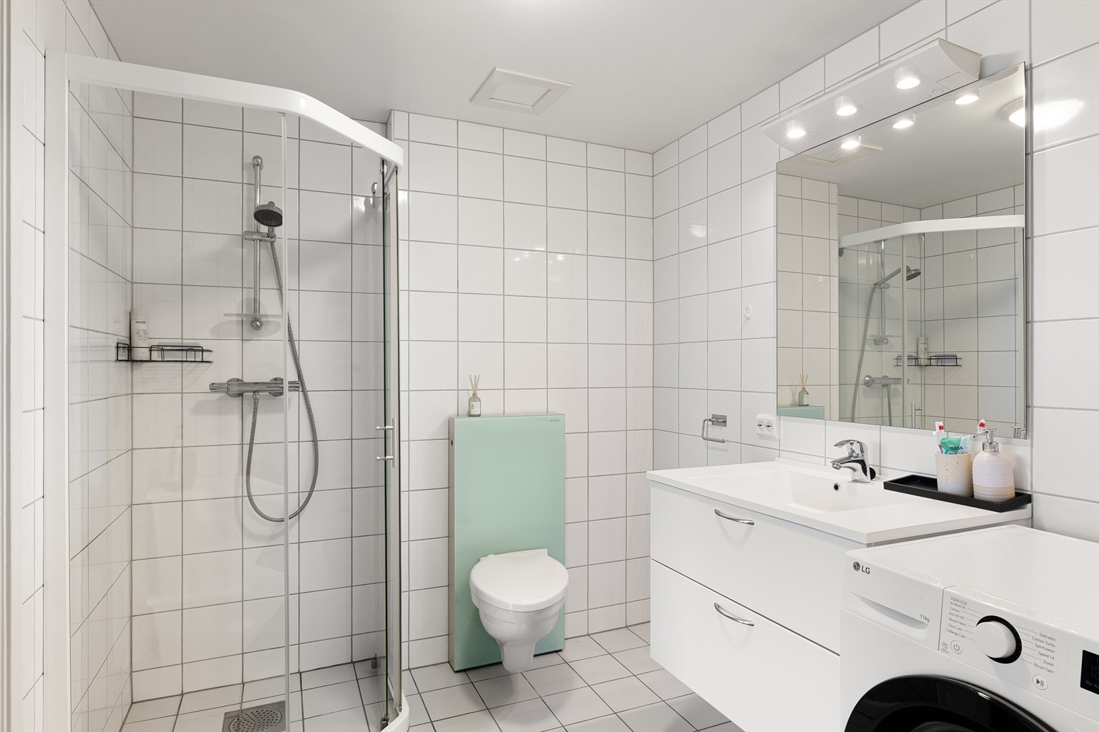 Badet har baderomsinnredning med nedfelt vask, speil med overlys, vegghengt toalett, dusj, og opplegg til vaskemaskin. Galleribilde