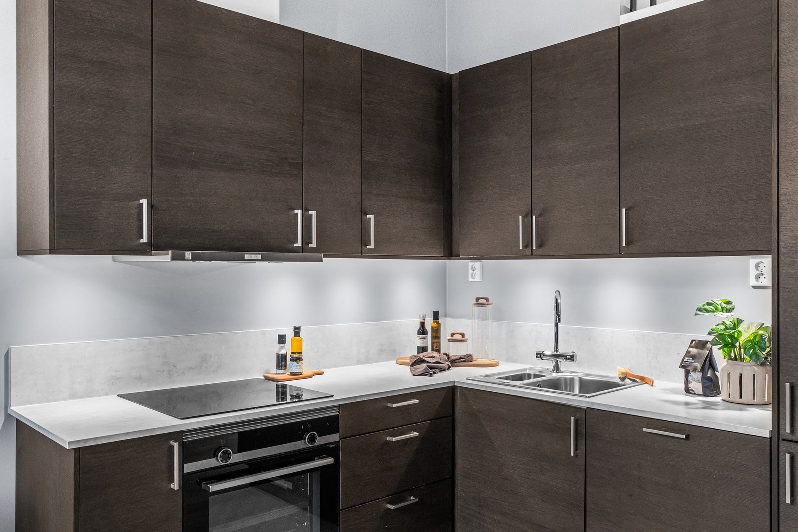 Pent kjøkken med integrerte hvitevarer og rikelig med skap- og benkeplass Galleribilde