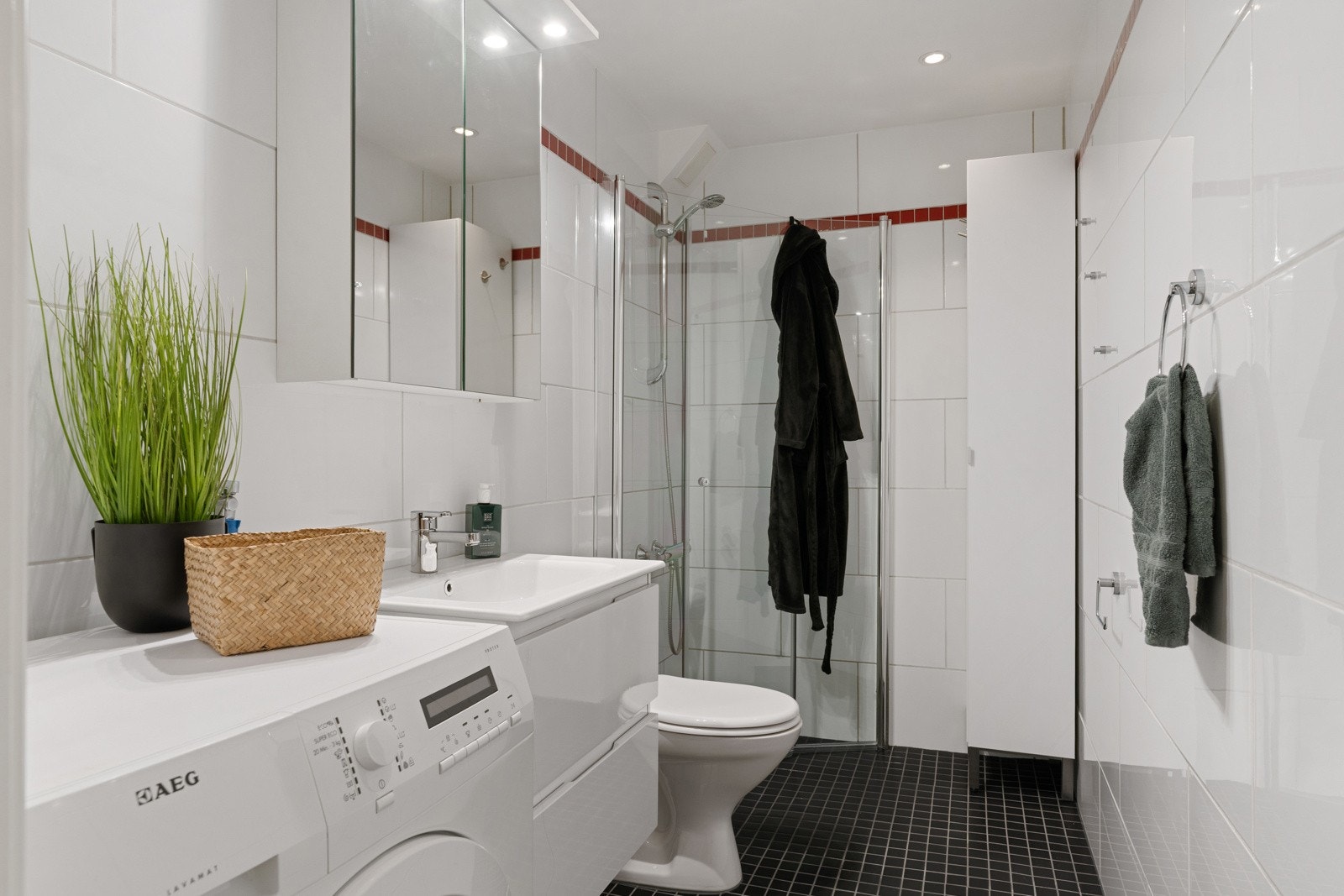 Badet måler 4 m² og er utstyrt med dusjhjørne, servant med skuffeseksjoner, speilskap, toalett og opplegg for vaskemaskin. Galleribilde