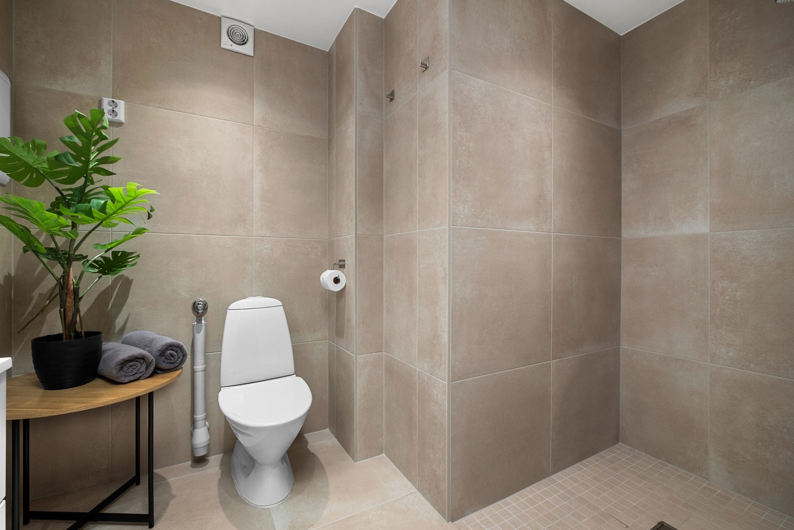 Badet er innredet med veggmontert servantinnredning og speilskap med overlys. Gulvmontert toalett. Dusjhjørne og opplegg for vaskemaskin Galleribilde