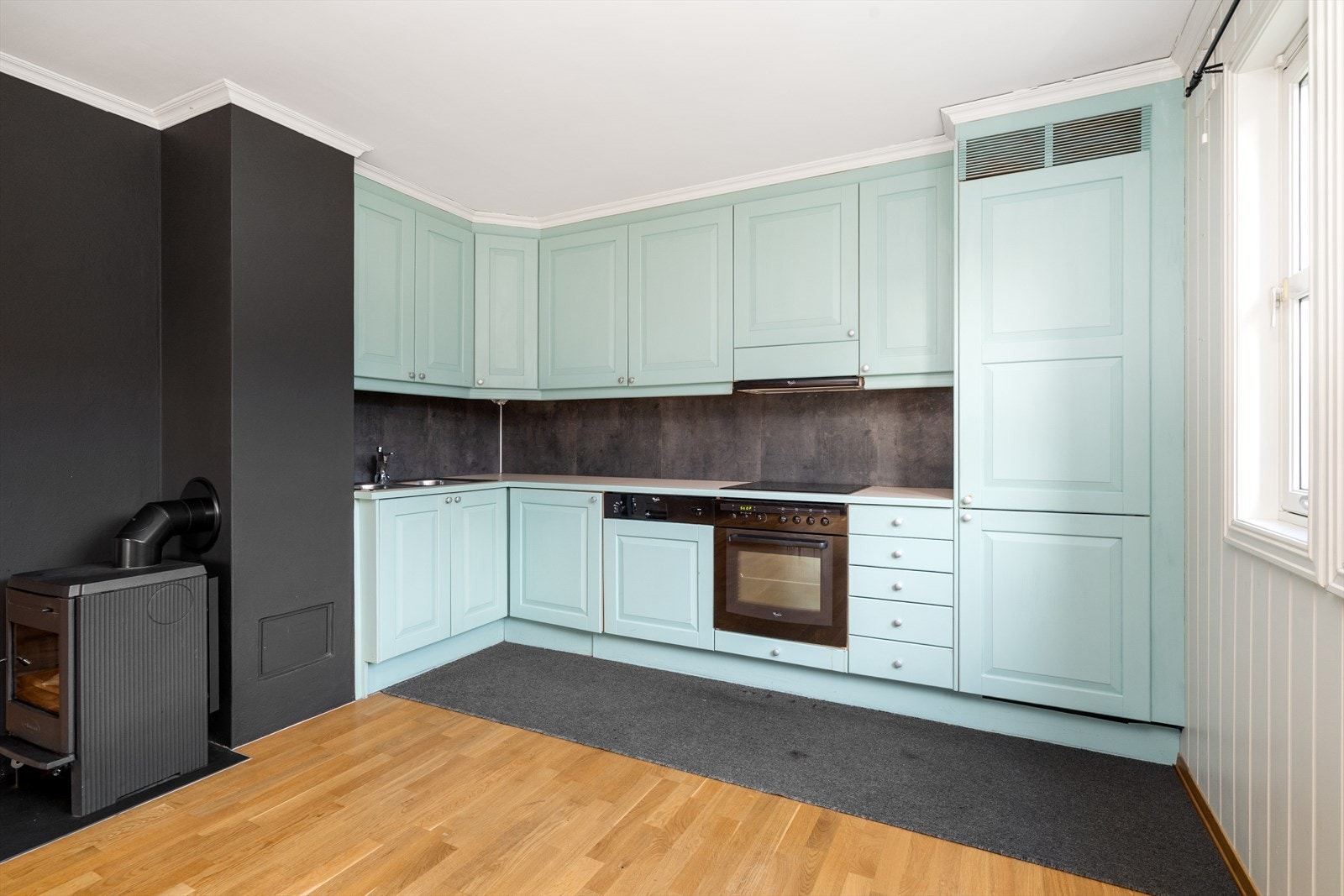 Kjøkkenet har takhøy innredning med god oppbevaringsplass, malte, profilerte fronter og laminert benkeplate. Integrerte hvitevarer er oppvaskmaskin, koketopp, stekeovn og kjøl/fryseskap. Galleribilde