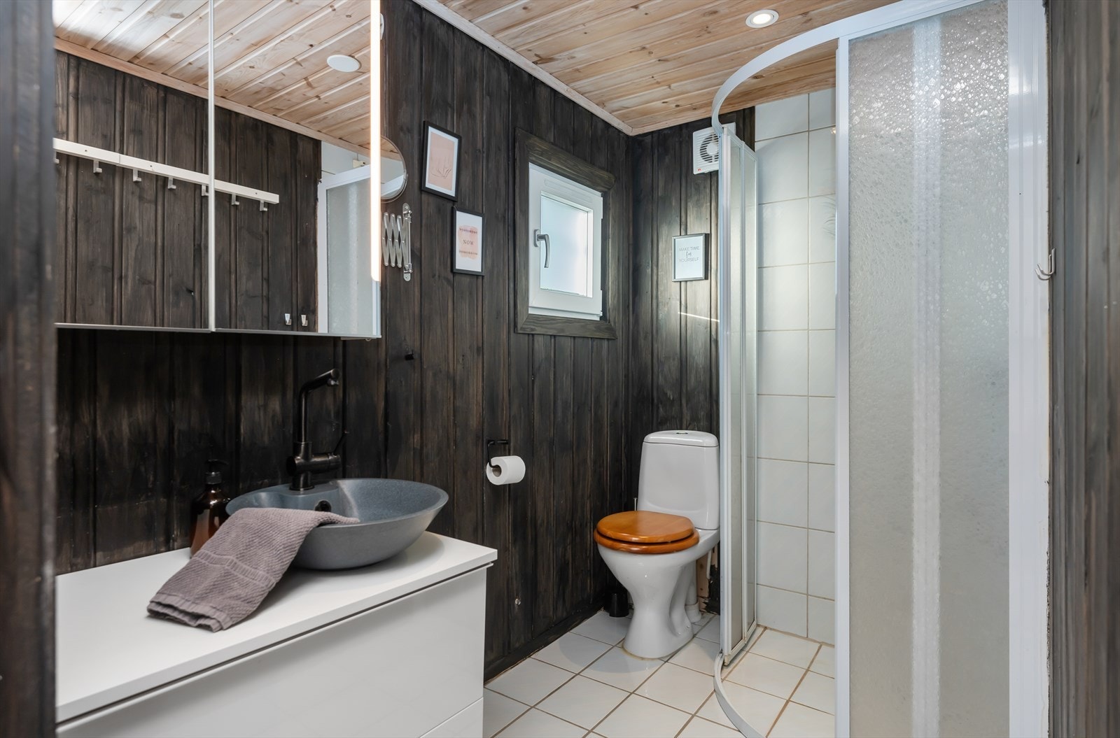 Flislagt bad med toalett, baderomsinnredning med underskuffer og skapseil, samt dusjkabinett. Galleribilde