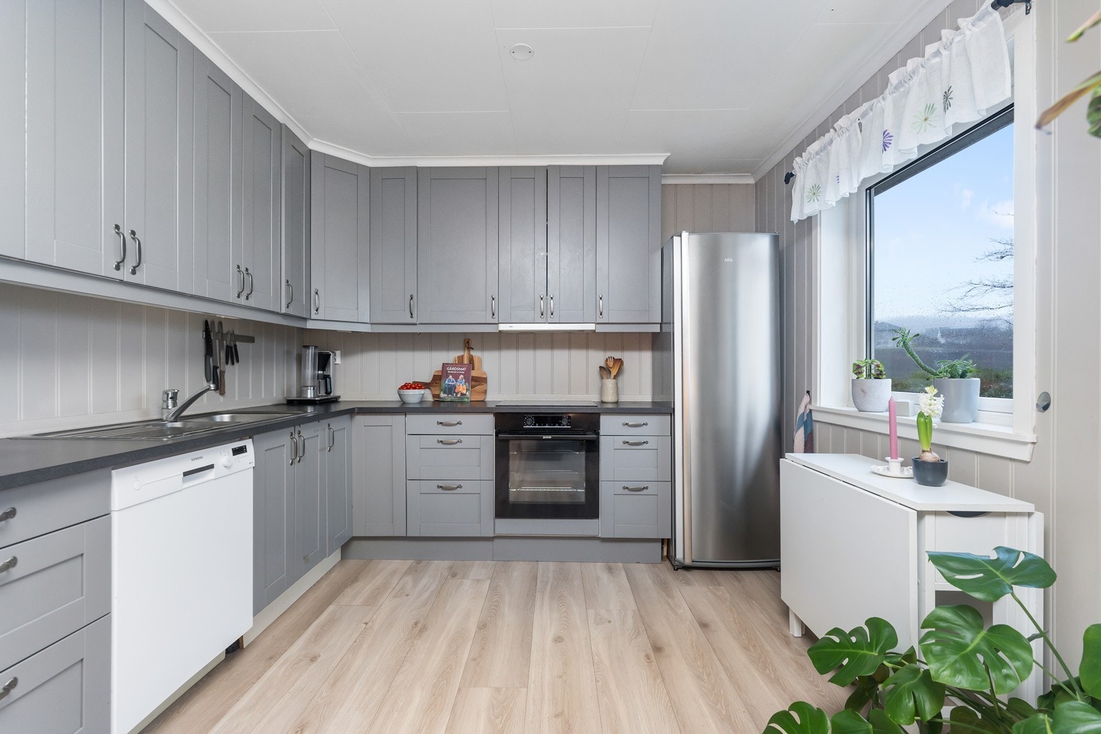 Kjøkkeninnredning med masse lagringsplass og arbeidsflate på benk. Her er også plass til spisebord. Galleribilde