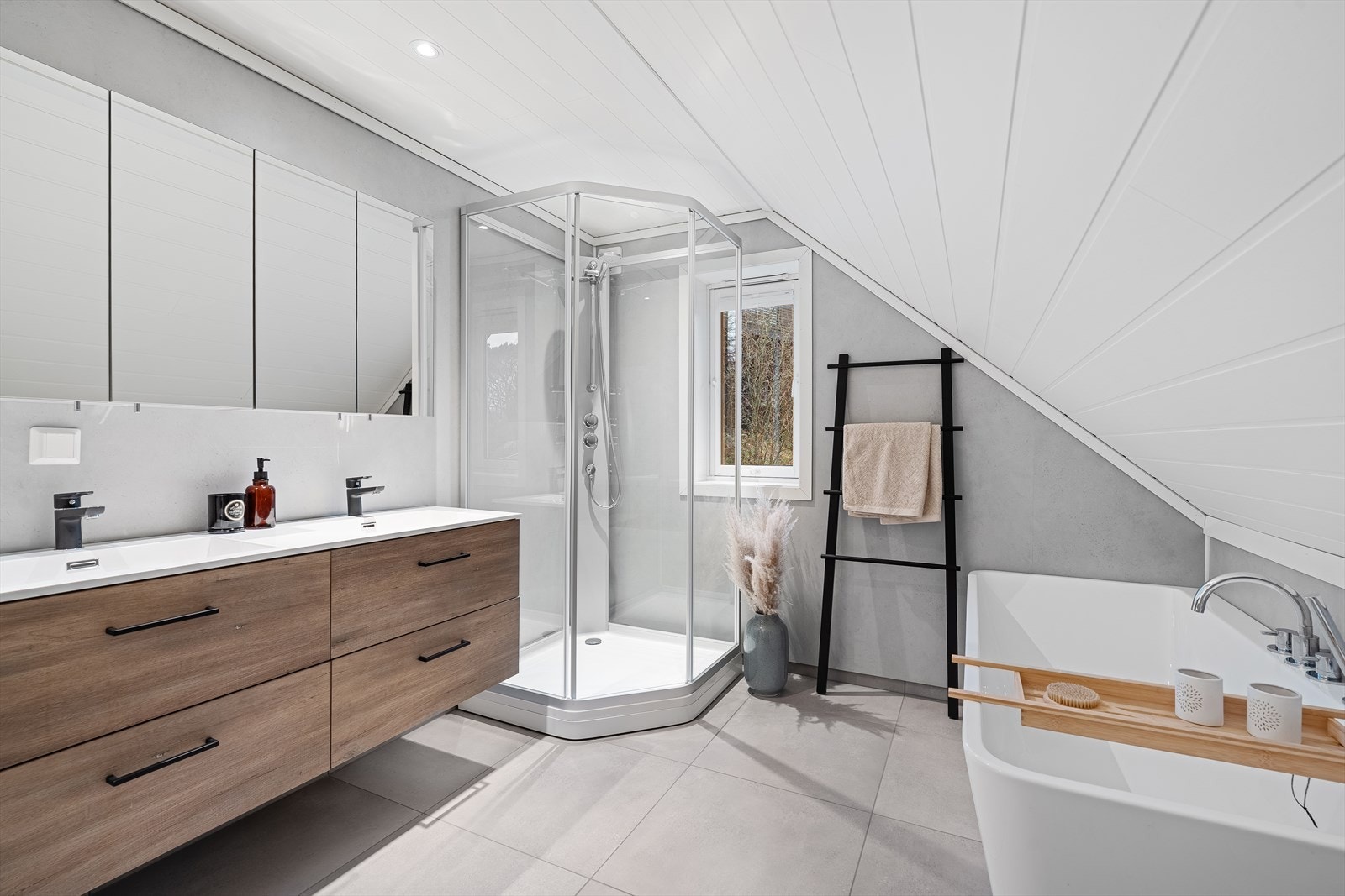 Badet i loftsetasjen har fliser på gulvet med varmekabler, og inneholder forøvrig badekar, dusjkabinett, baderomsinnredning med dobbel vask og speilskap, samt toalett. Via skapdør i kneveggen er det gjennomgang til ekstra oppbevaringsplass! Galleribilde