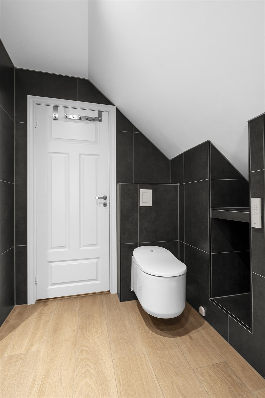 Badet er utstyrt med heldekkende servantplate over skuffeinnredning, overliggende speil, vegghengt toalett, dusjnisje og opplegg til vaskemaskin og tørketrommel Galleribilde