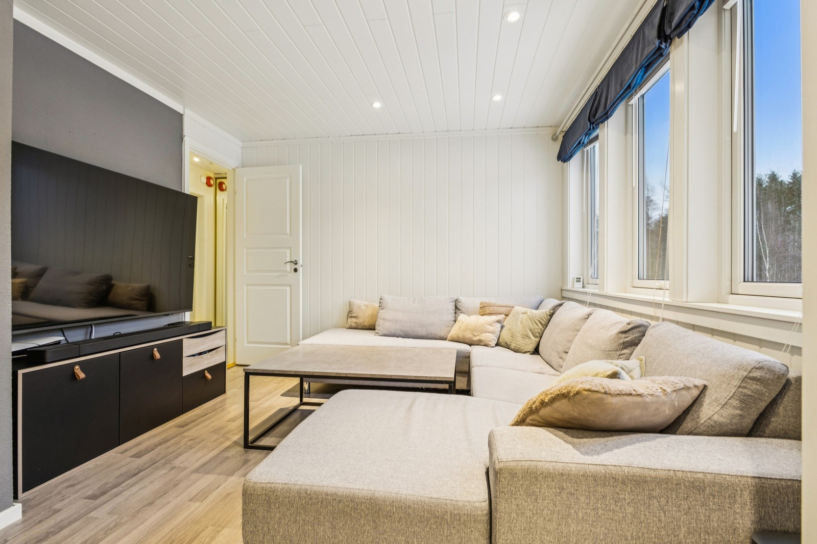 Rommene fremstår som innbydende med moderne materialvalg og god belysning via downlights på stue og kjøkken. Galleribilde