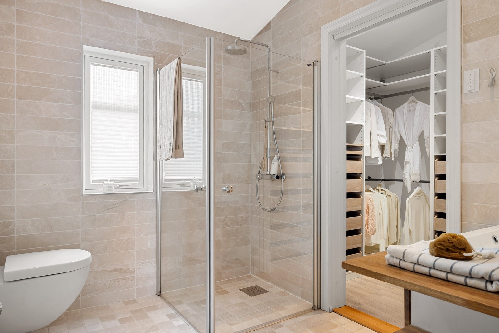 Innredet med dusjhjørne med glassvegger, vegghengt toalett og baderomsinnredning. Galleribilde