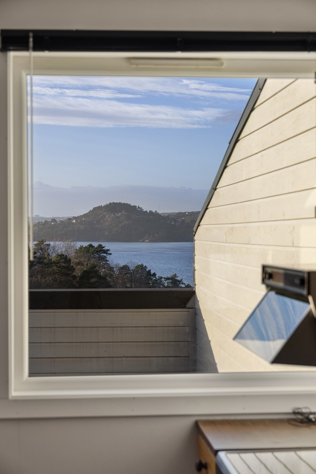 Utsikt fra vindu mot sjøen gir en naturskjønn ramme for oppholdsrommet. Galleribilde