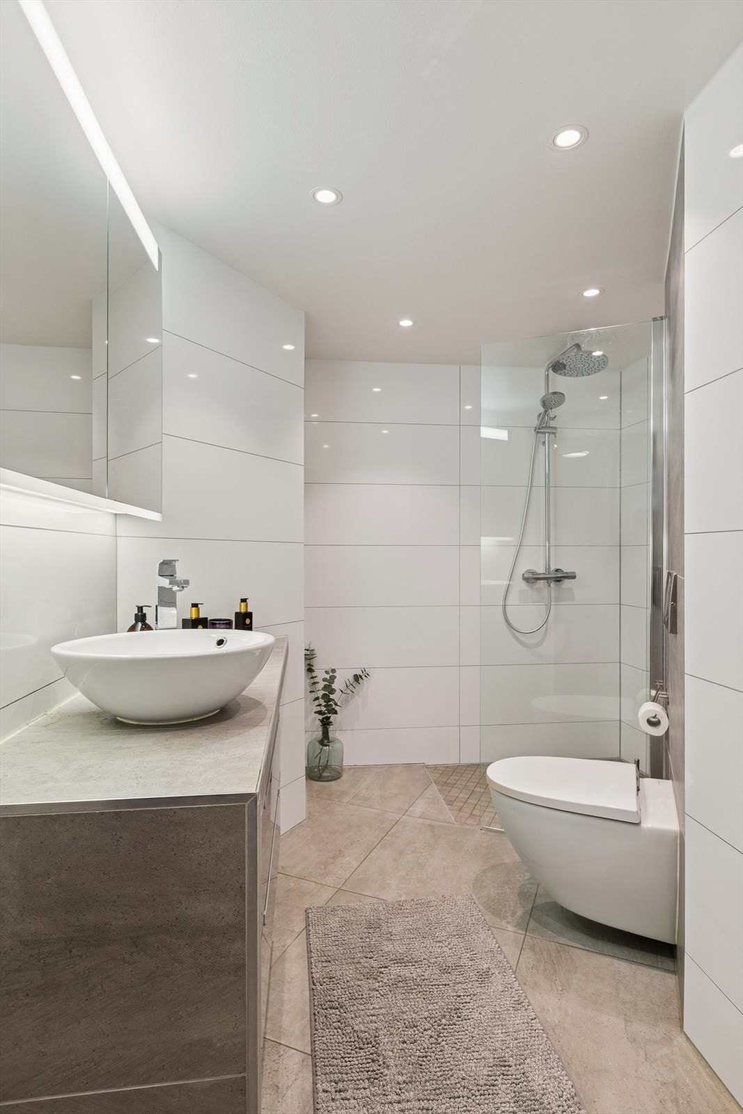 Moderne bad fra 2015 i delikate farger. Badet består av servant med underskuffer, speilskap, vegghengt toalett og dusjnisje. Galleribilde