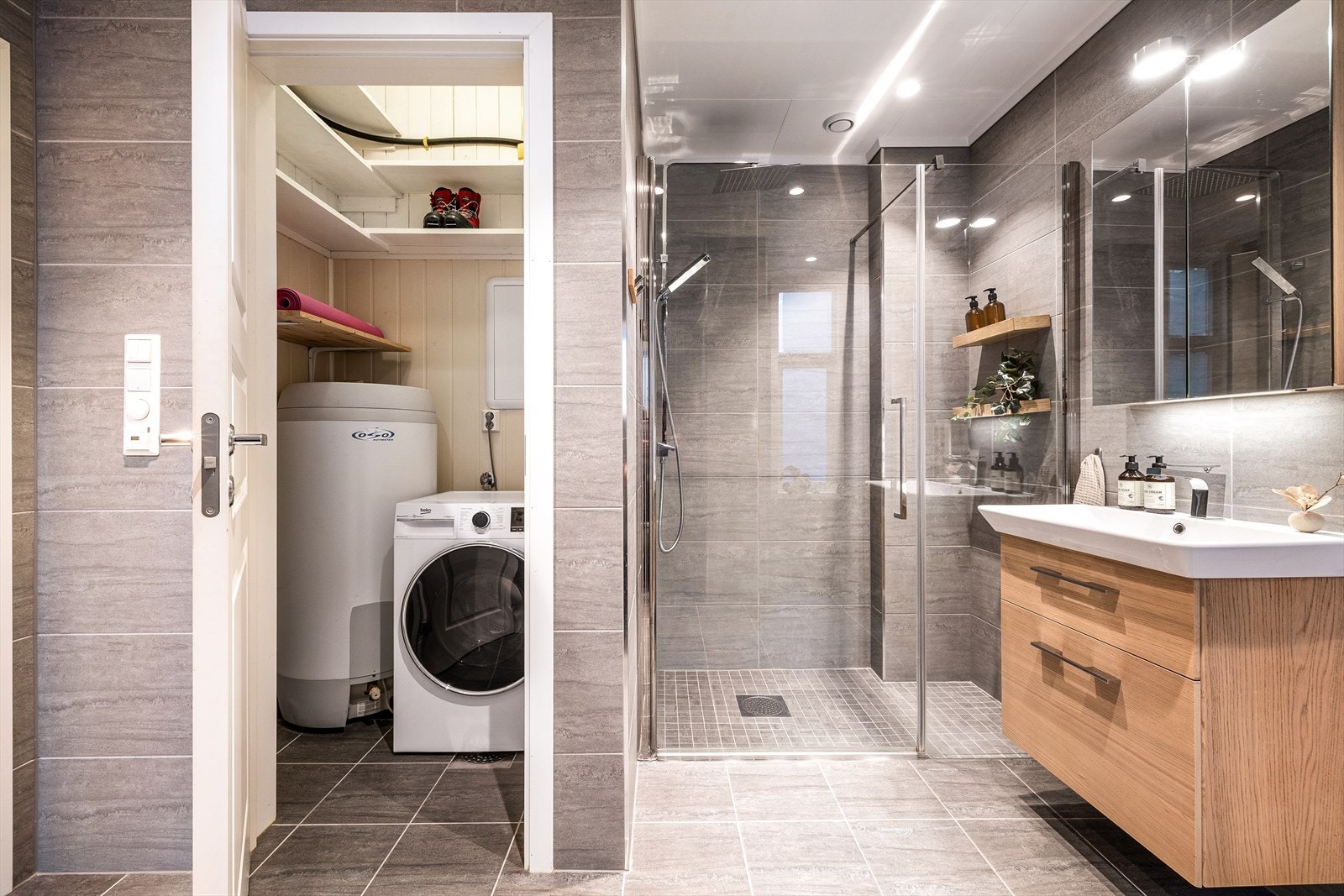 Badet er innredet med benkeskap med servant, dusjsone med glassdør og vegghengt toalett. Galleribilde