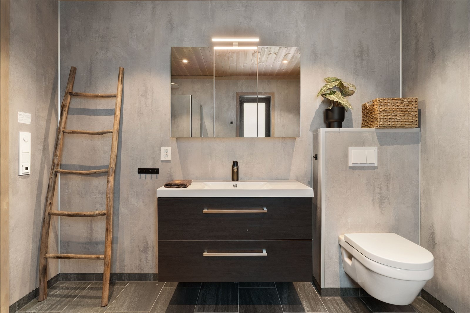 Pent og moderne innredet med speilskap over servant og vegghengt toalett Galleribilde