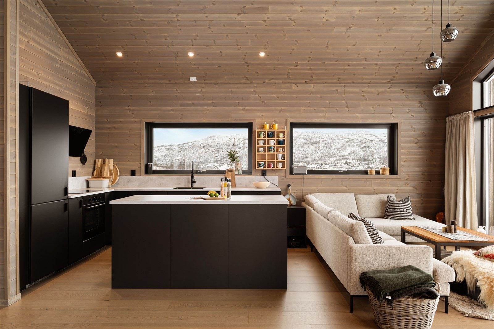 Hytten har et mørkt og lekkert kjøkken med åpen løsning Galleribilde