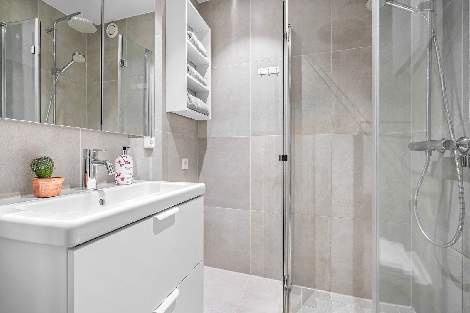 Badet er innredet med et dusjhjørne med regnfallsdusj og innfellbare glassdører. Galleribilde