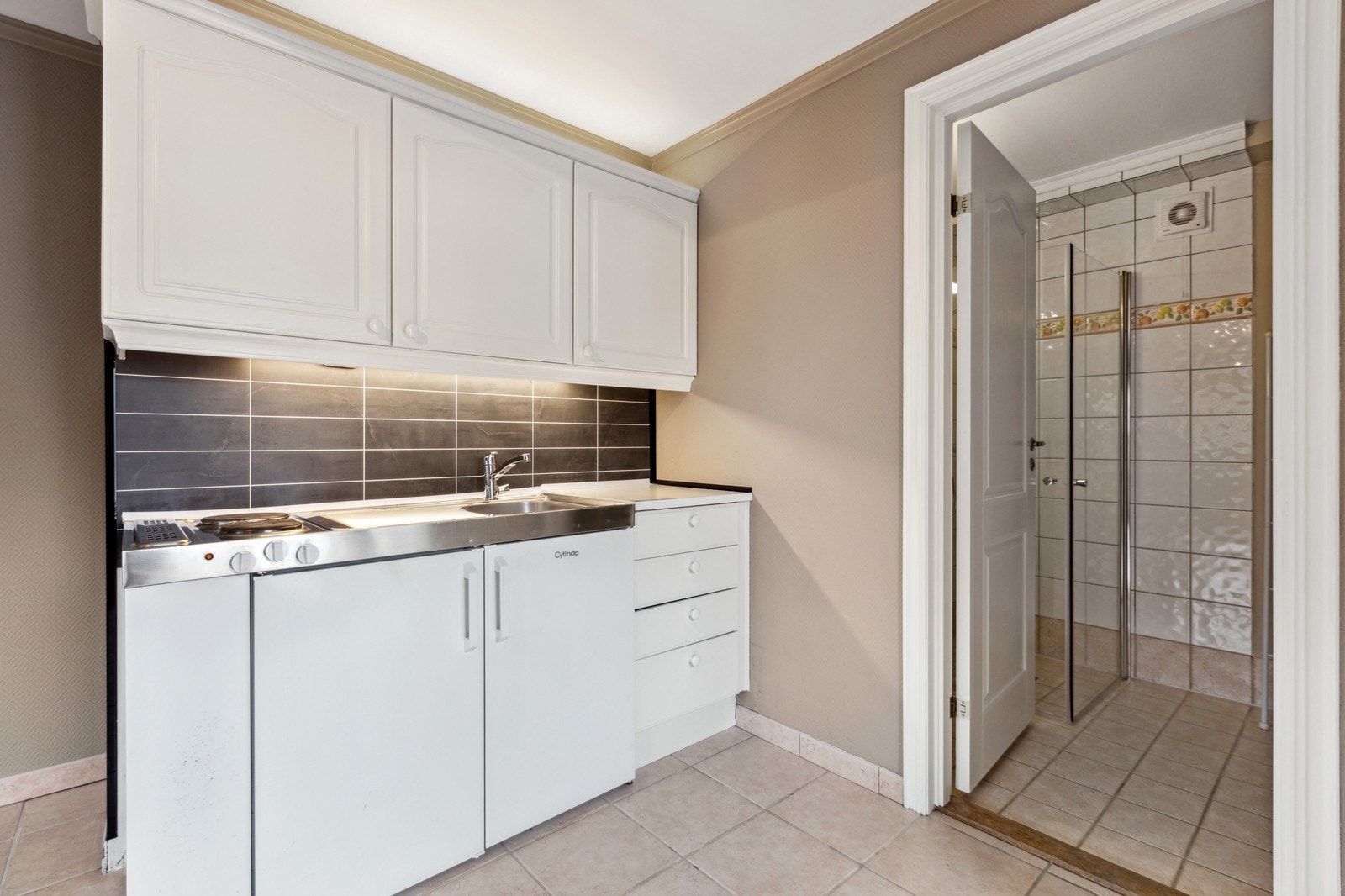 Kjøkken med to kokeplater, lite kjøleskap og vask Galleribilde