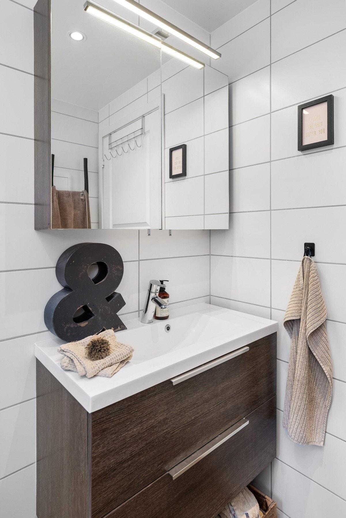 Baderomsinnredningen består av vegghengt toalett, helstøpt servant, skuffer under servant med slette fronter, og dusjdører i klart glass. Galleribilde