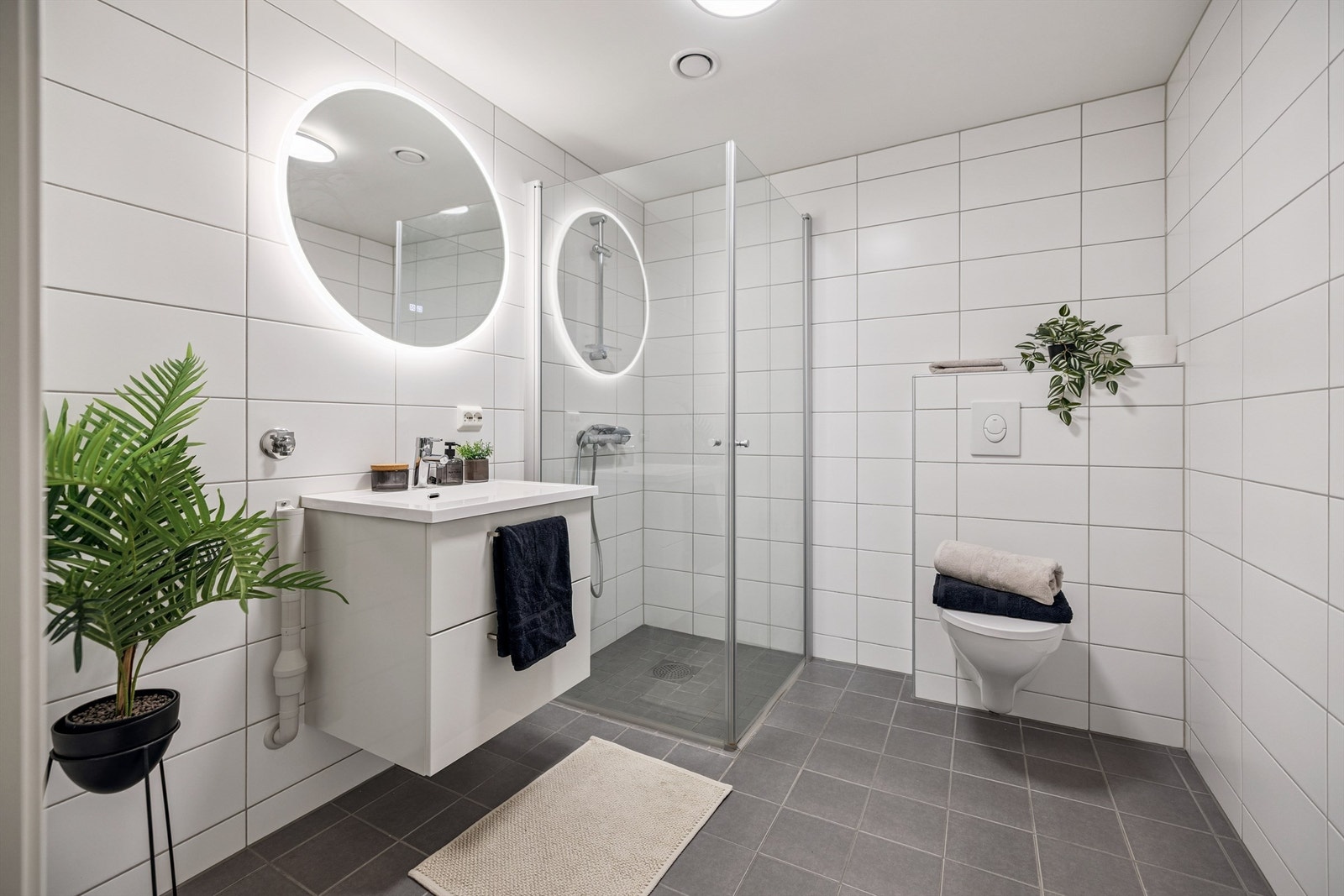 Badet er utstyrt med vegghengt toalett og dusjhjørne med innfellbare glassdører. Galleribilde