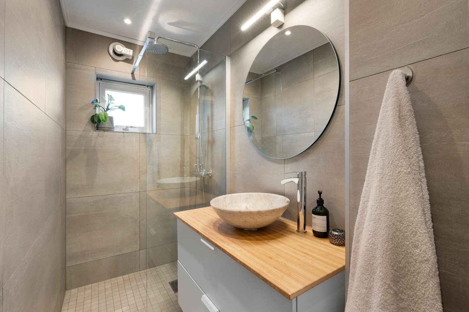 Lekkert flislagt bad med varmekabler i gulv. Regndusj og godt med oppbevaring i innredning. Galleribilde