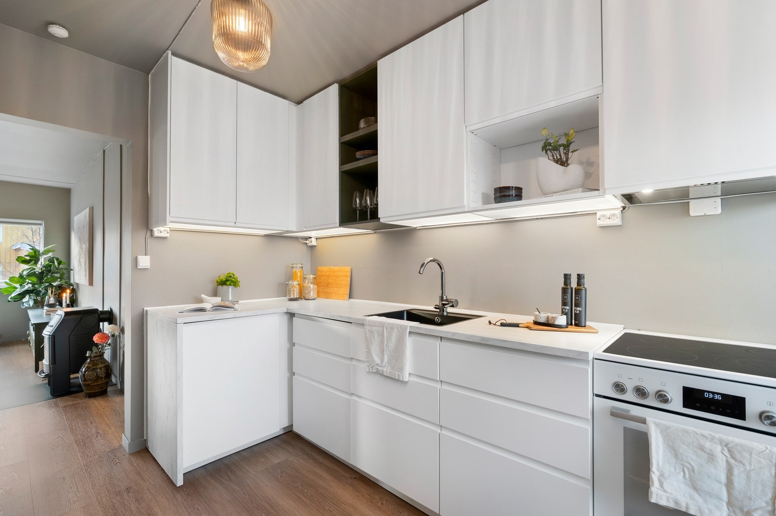 Tidløst kjøkken med hvite, slette fronter. Gjennomgående gulv og fargevalg gjør at rommet blir en naturlig forlengelse av stuen. Galleribilde